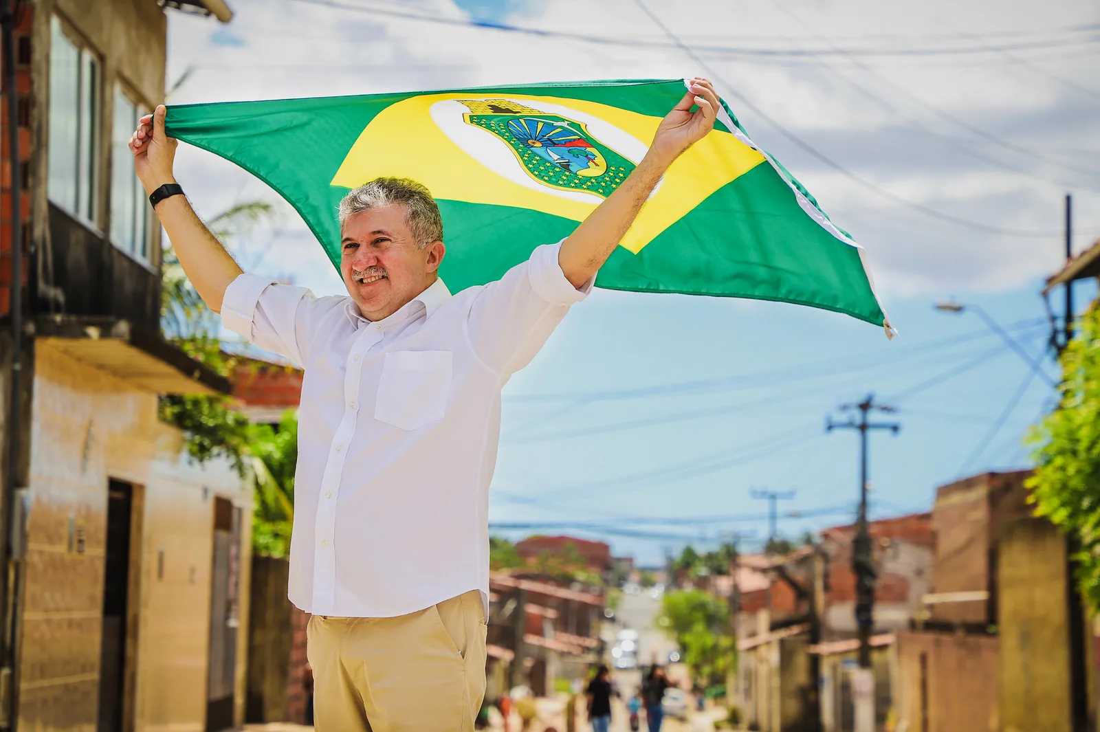 Antônio Henrique ergue a bandeira do Ceará no meio de uma rua de comunidade.