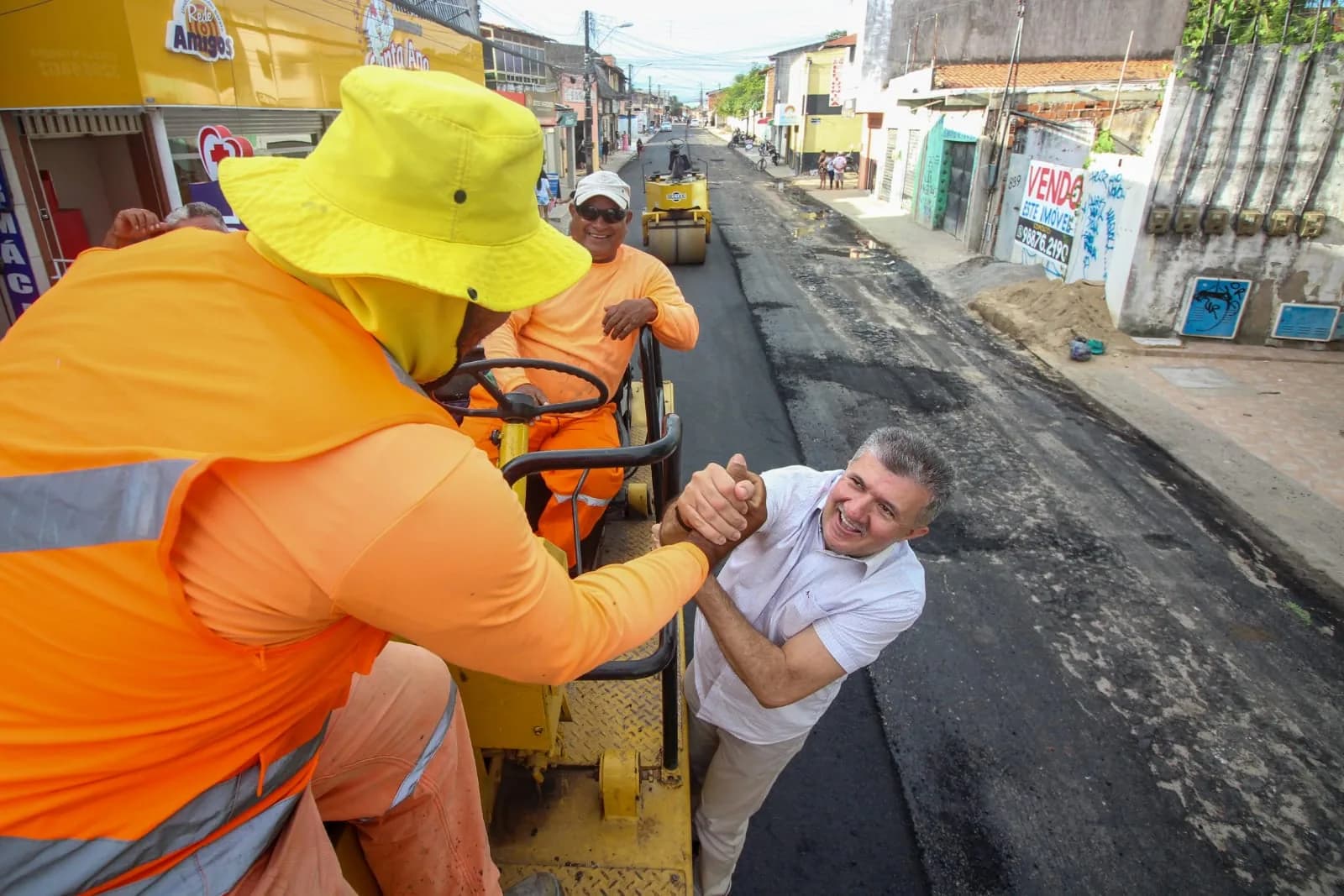 Antônio Henrique cumprimenta trabalhadores durante a pavimentação de ruas no Aracapé, em Fortaleza.